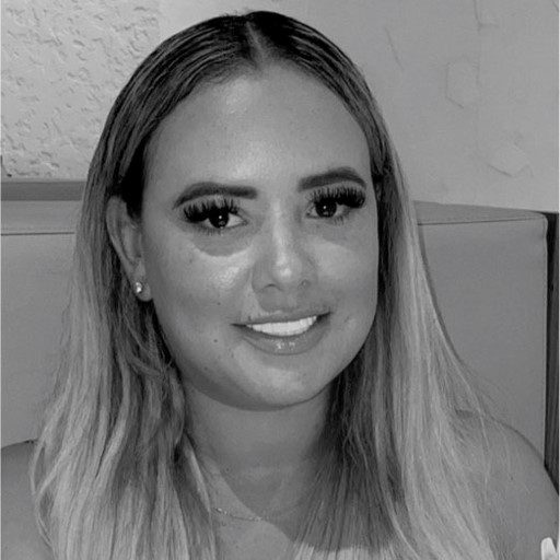 A woman with long, blonde hair and makeup is smiling. She is seated against a neutral background, conveying a friendly and approachable demeanor.